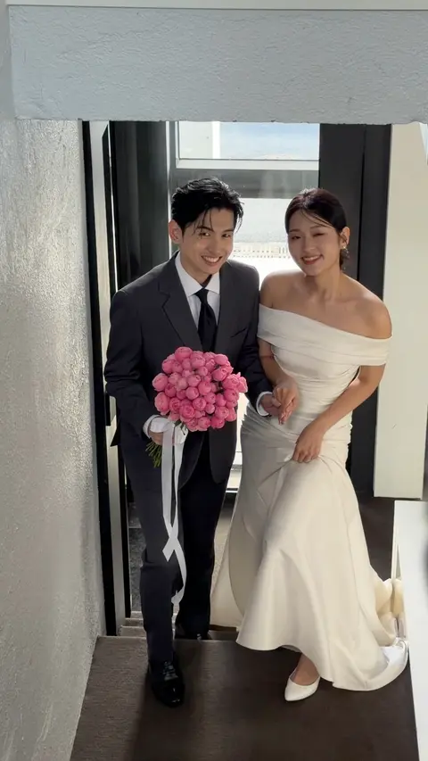 계단을 오르며 돌아보는 두 사람. 신랑이 분홍 부케를 들었다 (영상)